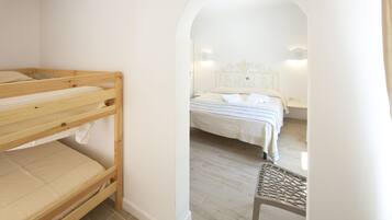 A room with a bunk bed, a single bed, and a chair.