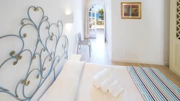 Un dormitorio con cabecera de metal, cama con ropa de cama blanca, alfombra a rayas y vistas a un balcón.