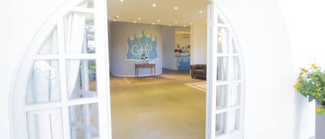 Una habitación con un amplio arco de entrada, una pequeña mesa con un florero y una silla.