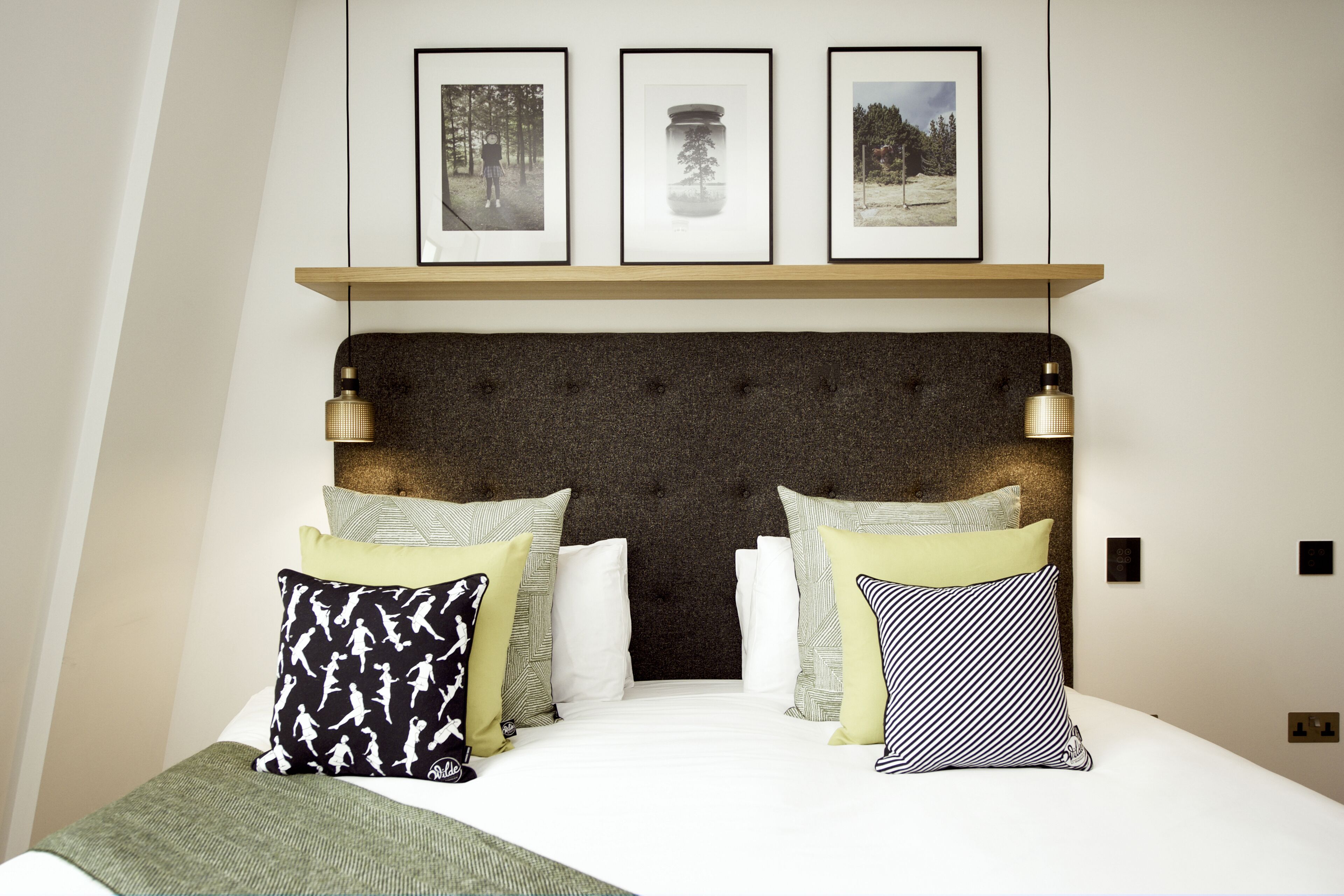 Ein Schlafzimmer mit einem mit Wirbeln verzierten Kopfteil, einem Bett mit weißen Leinen und drei gerahmten Bildern darüber.