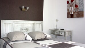 Een slaapkamer met een bed, een nachtkastje, een wandlamp en een schilderij.