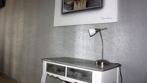 Een hoekbureau met een lamp, een lijst met een afbeelding aan de muur, en een gestructureerde wand.