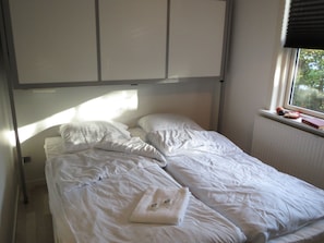 A single bed with white bedding, a window with blinds, and a radiator. - Danhostel Rebild (Skorping)