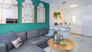 A modern living room with a grey sofa, a round coffee table with decorative bottles, and a teal accent wall.