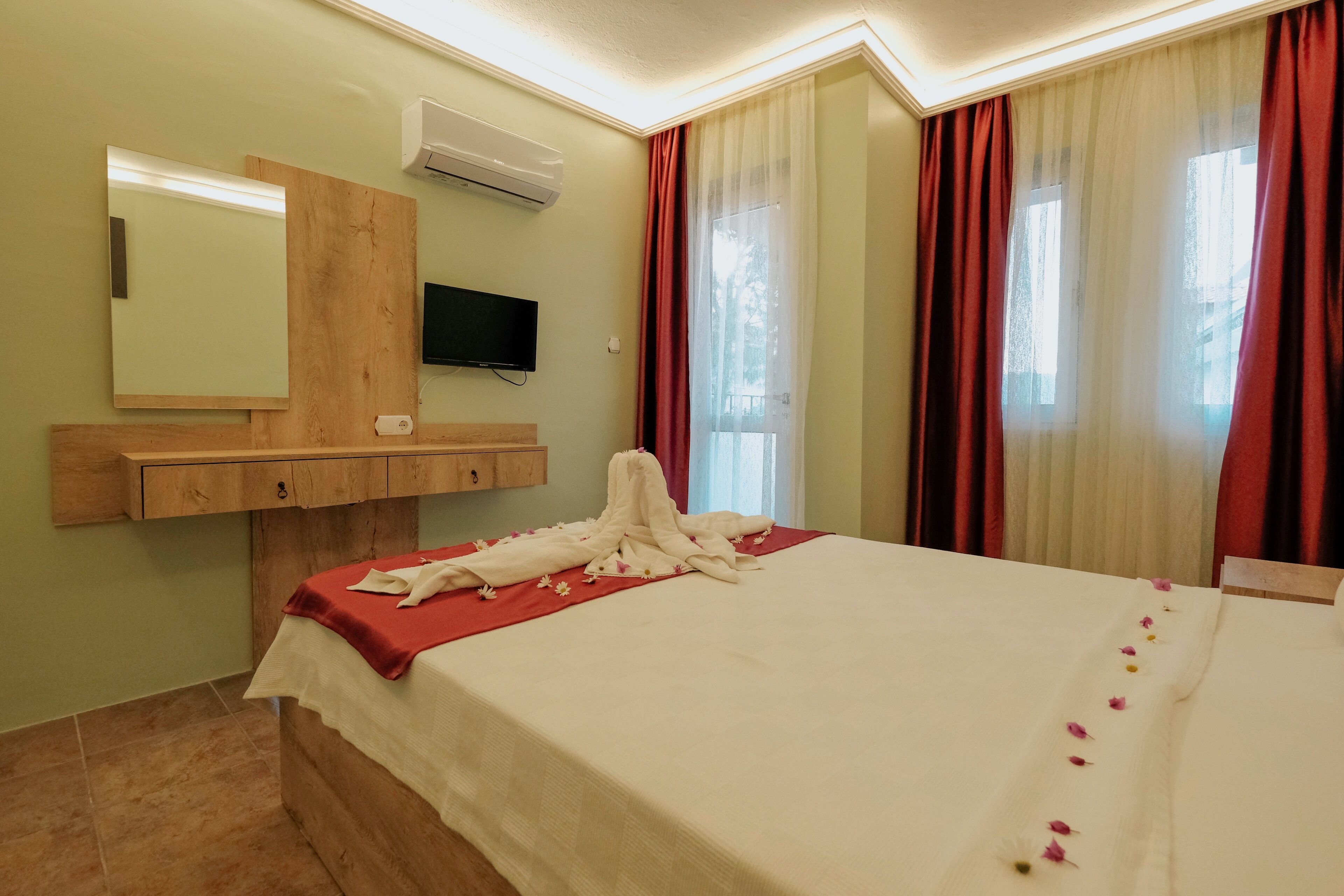 Ein Hotelzimmer mit einem Bett, einem Holzkopfschild, einem Fernseher, einem Spiegel und einem Fenster mit Vorhängen.