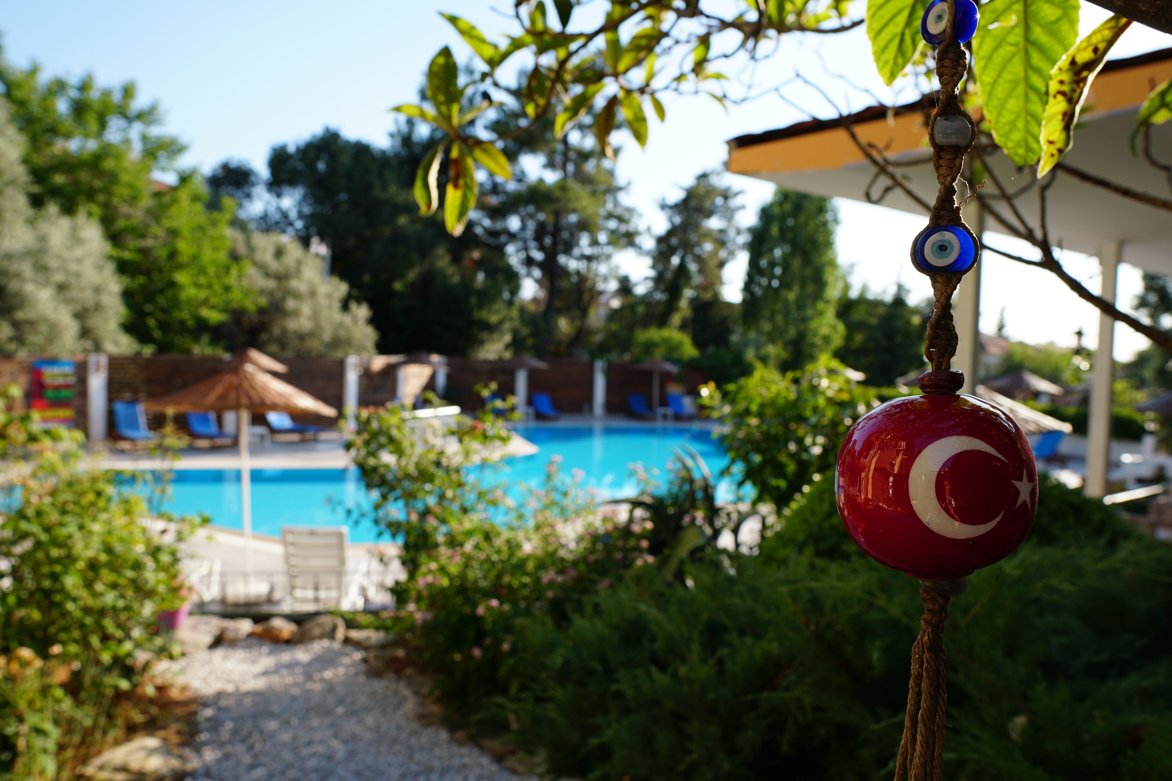Un área de piscina con una bandera roja, una azul y una blanca en un asta.
