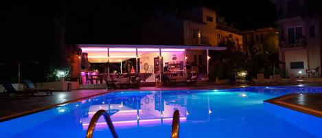 Una piscina con un área de bar al fondo.