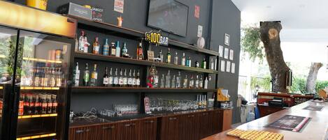 A bar area with shelves of bottles, a television, and a wooden counter.