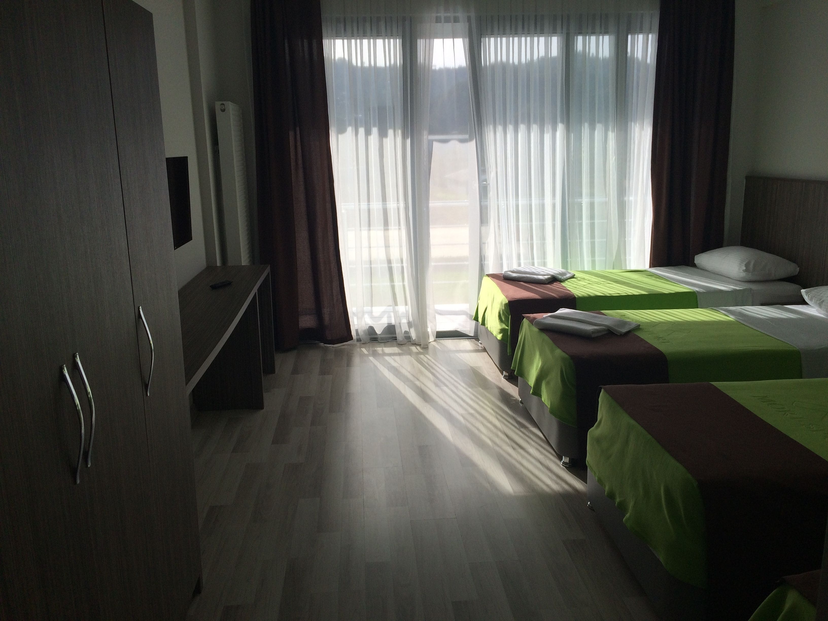 Ein Hotelzimmer mit zwei Betten, einem Schreibtisch und einem Kleiderschrank.