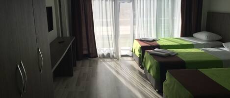 A hotel room with two beds, a desk, and a wardrobe.