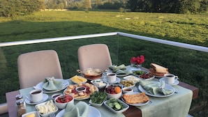 Mesa al aire libre con vista a un campo verde y colinas.