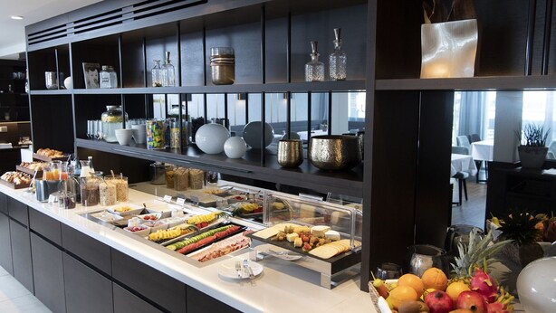 A buffet area with various food items and a selection of glassware and decorative items on shelves. - Hotel Schwanen Köngen (Kongen)