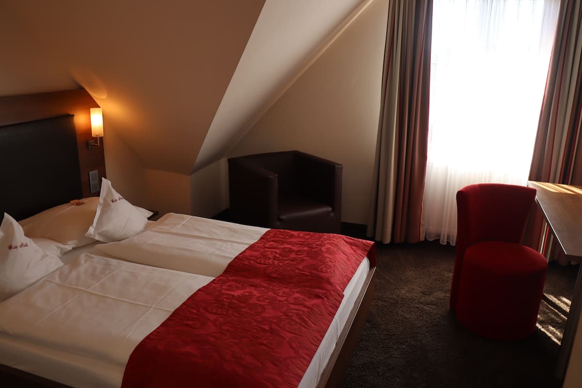 A hotel room with a bed, a desk, a chair, and a window with curtains.