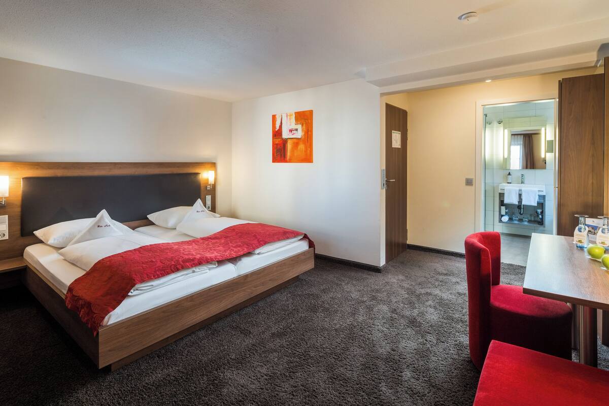 A hotel room with a bed, a desk, and a chair.