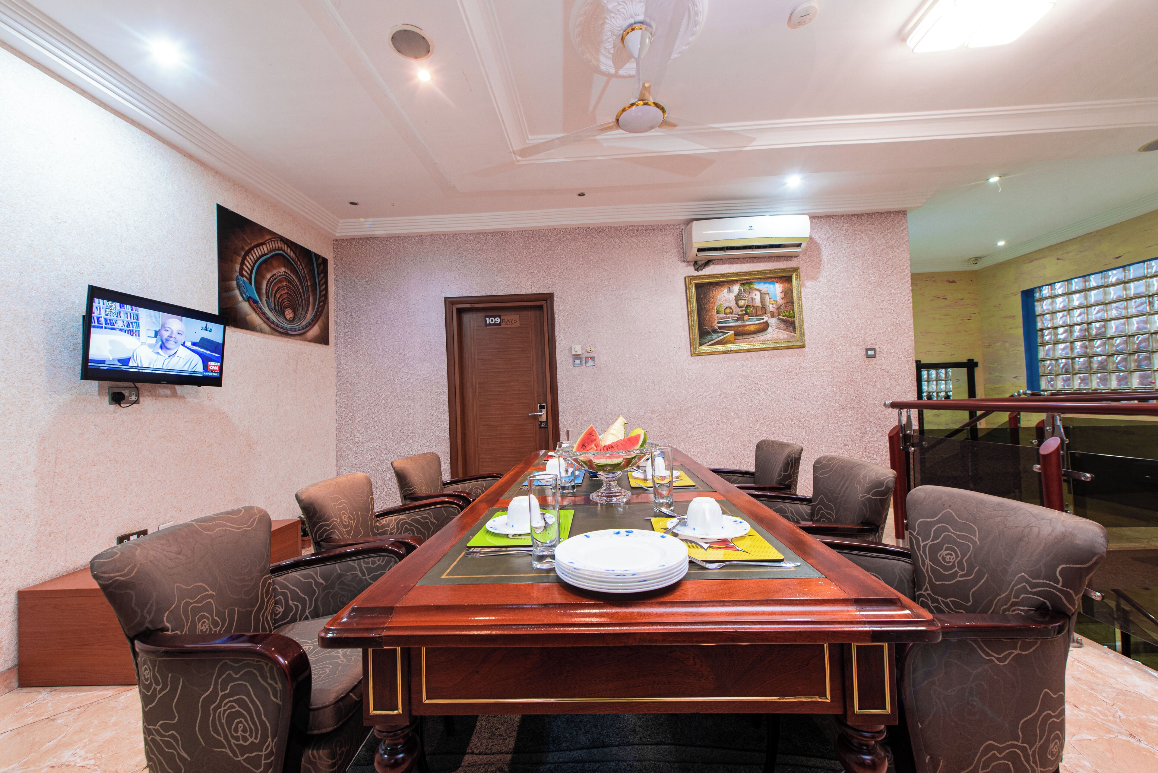 A conference room with a long table, chairs, a television, and a door.