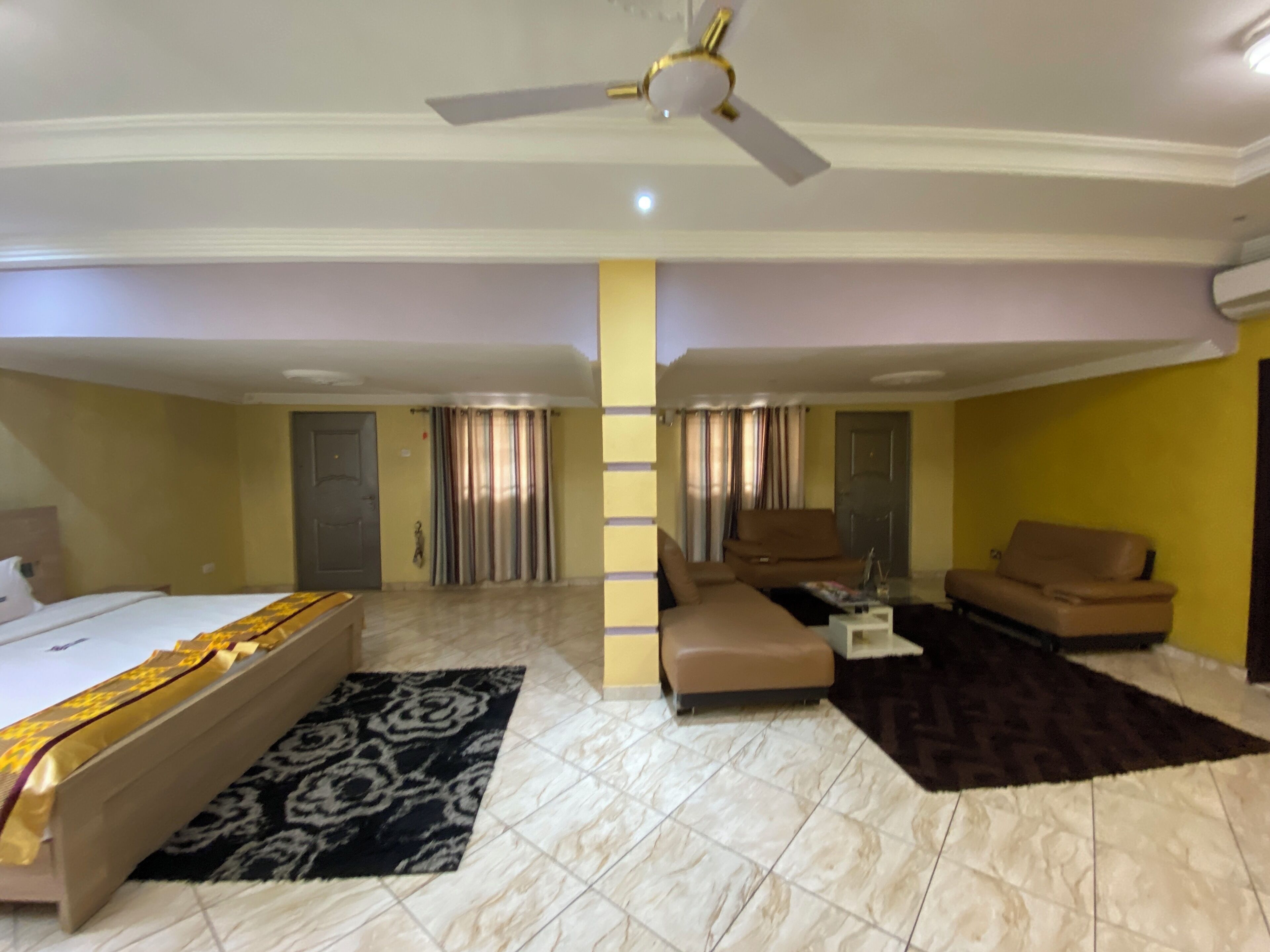 A hotel room with a bed, a sofa, a coffee table, and a ceiling fan.
