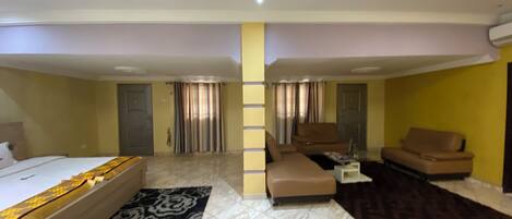 A hotel room with a bed, a sofa, a coffee table, and a ceiling fan.