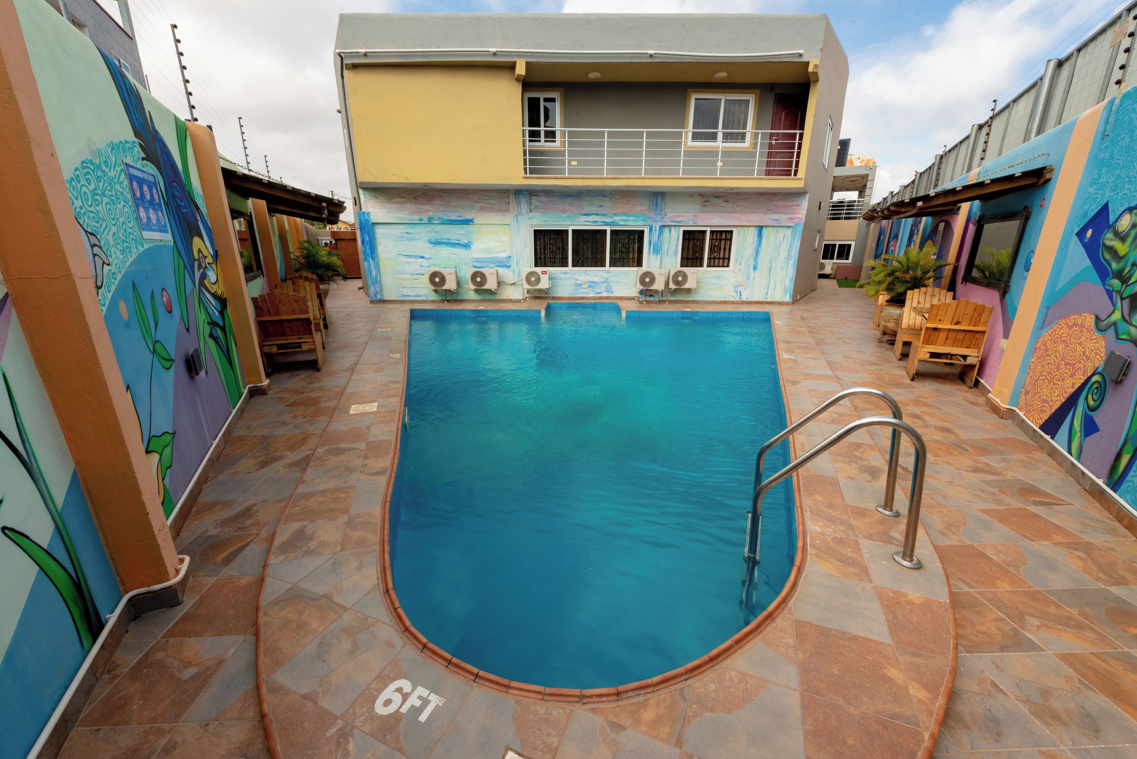 A swimming pool with a 6ft depth marker, surrounded by colorful walls with murals.