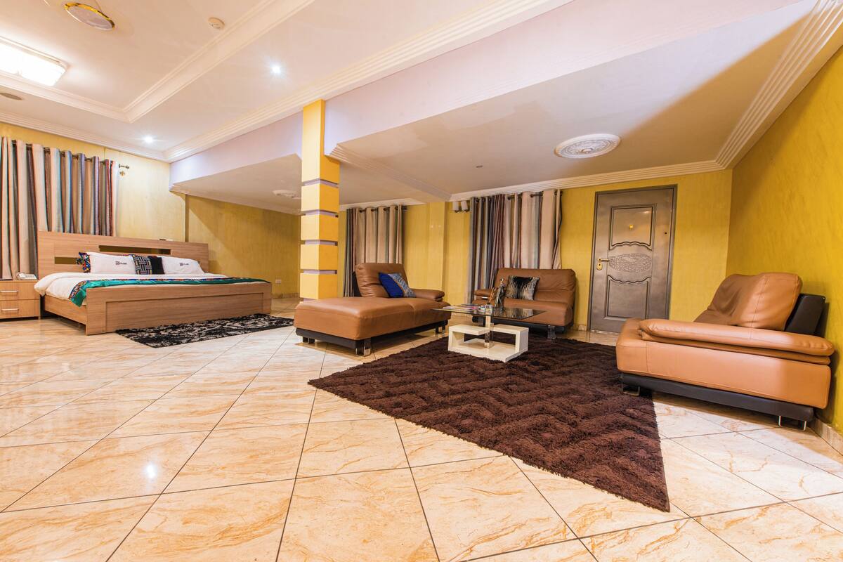 Una habitación de hotel moderna con una cama, dos sofás, una mesa de centro y una alfombra grande.