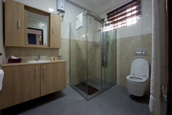 A bathroom with a glass-enclosed shower, a sink, and a toilet. - Bays Luxury Lodge (Accra)