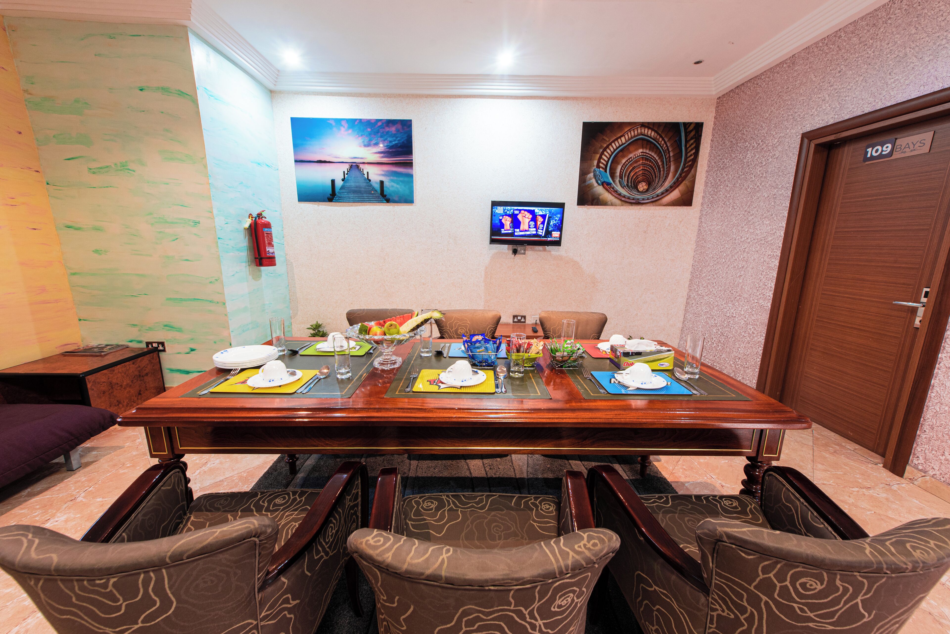 A dining area with a wooden table set for four, surrounded by patterned chairs.