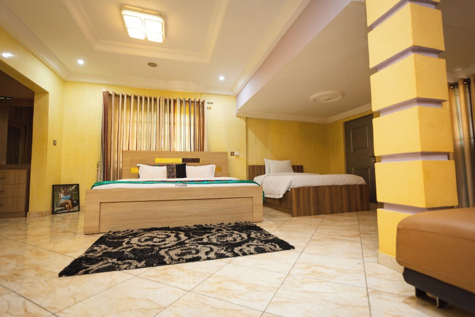 Une chambre d’hôtel avec un grand lit, un lit plus petit, un canapé et une salle de bain visible à travers une porte ouverte.