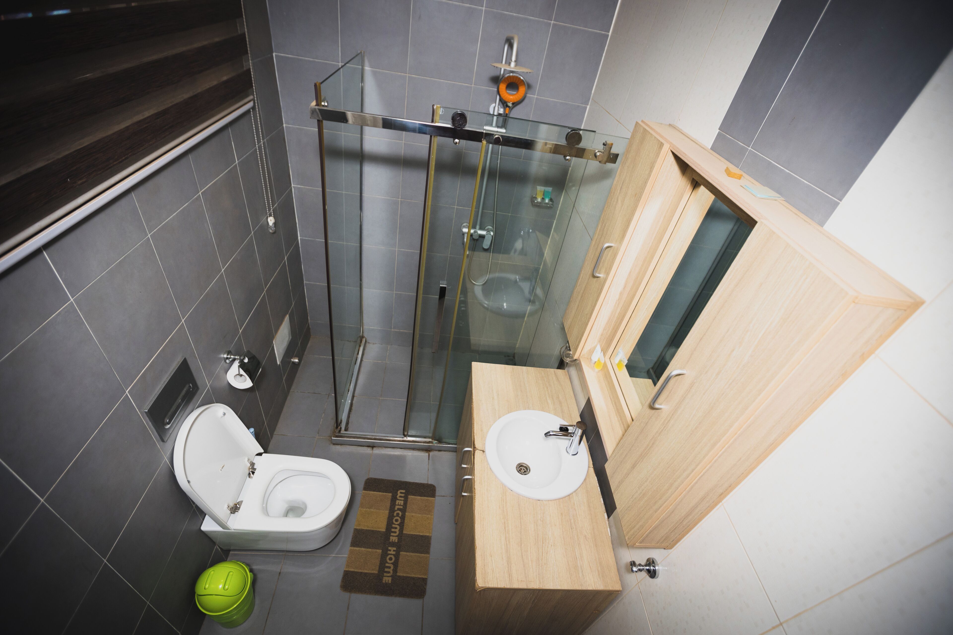 Et moderne badeværelse med en brusekabine i glas, en trækommode med vask og et toilet.