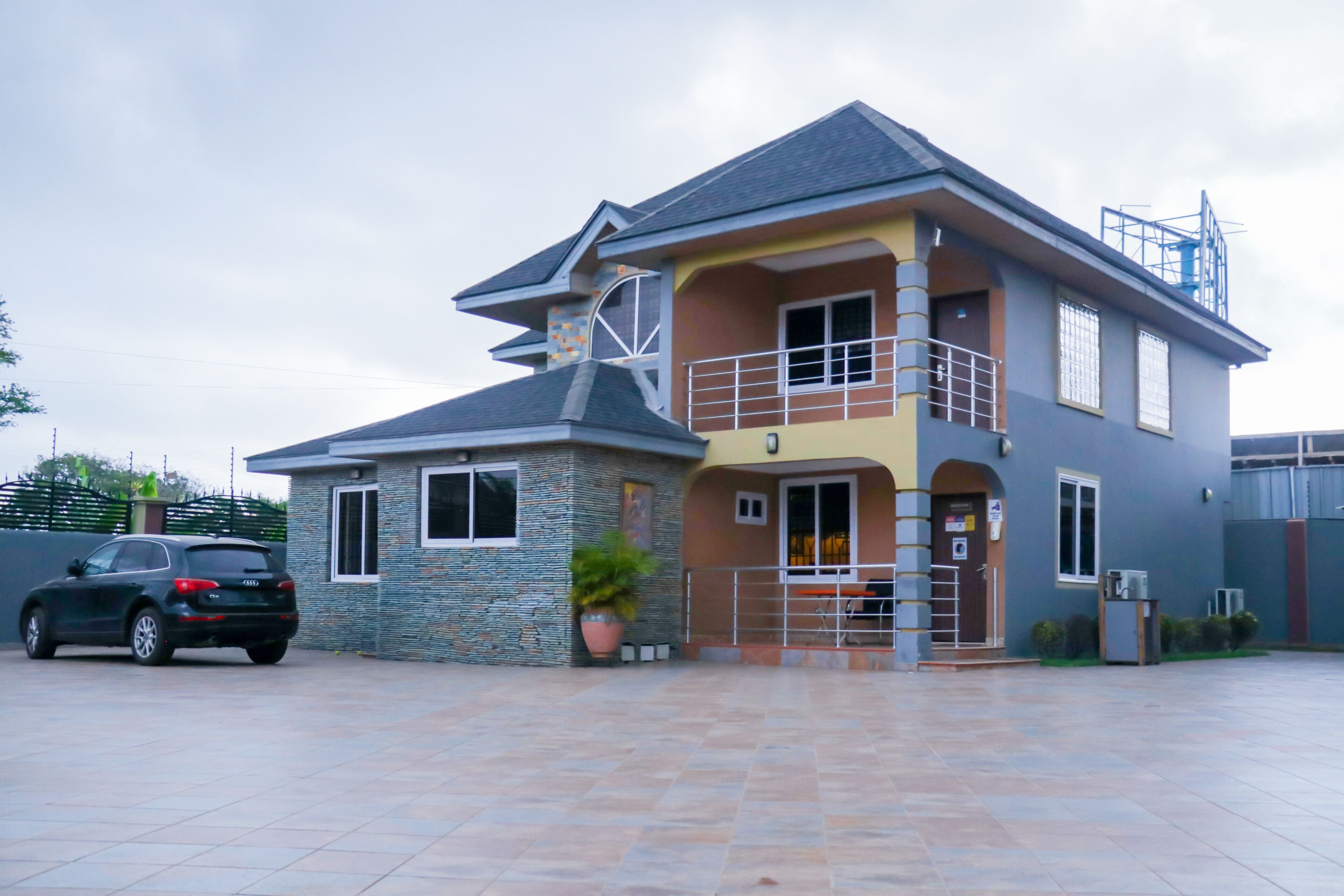 Une maison à deux étages avec un balcon, un garage et une façade en pierre.