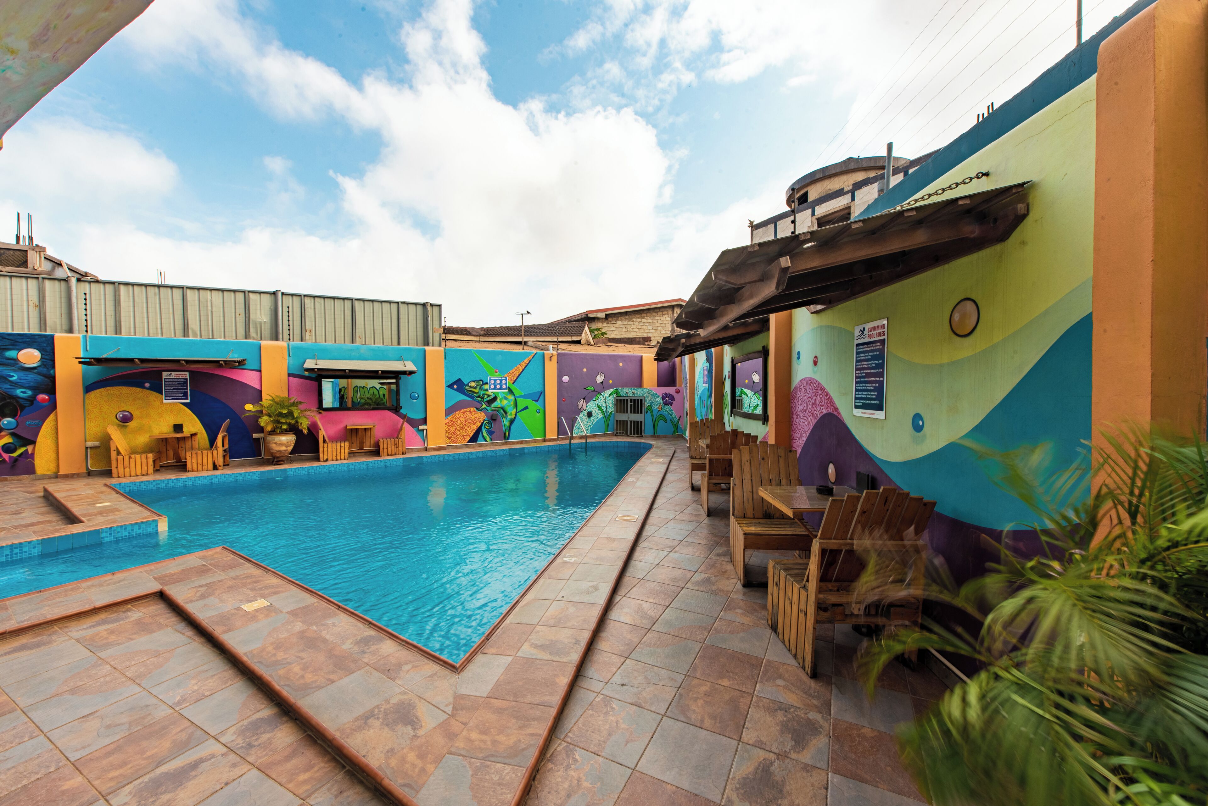 Una piscina con suelo de baldosas y sillones de madera.