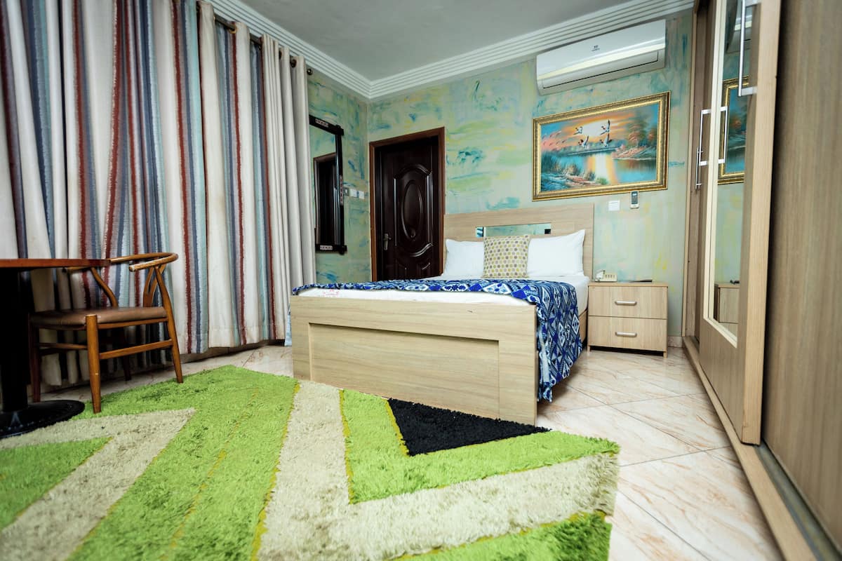 Un dormitorio con una cama, una silla, una mesita de noche y un armario.