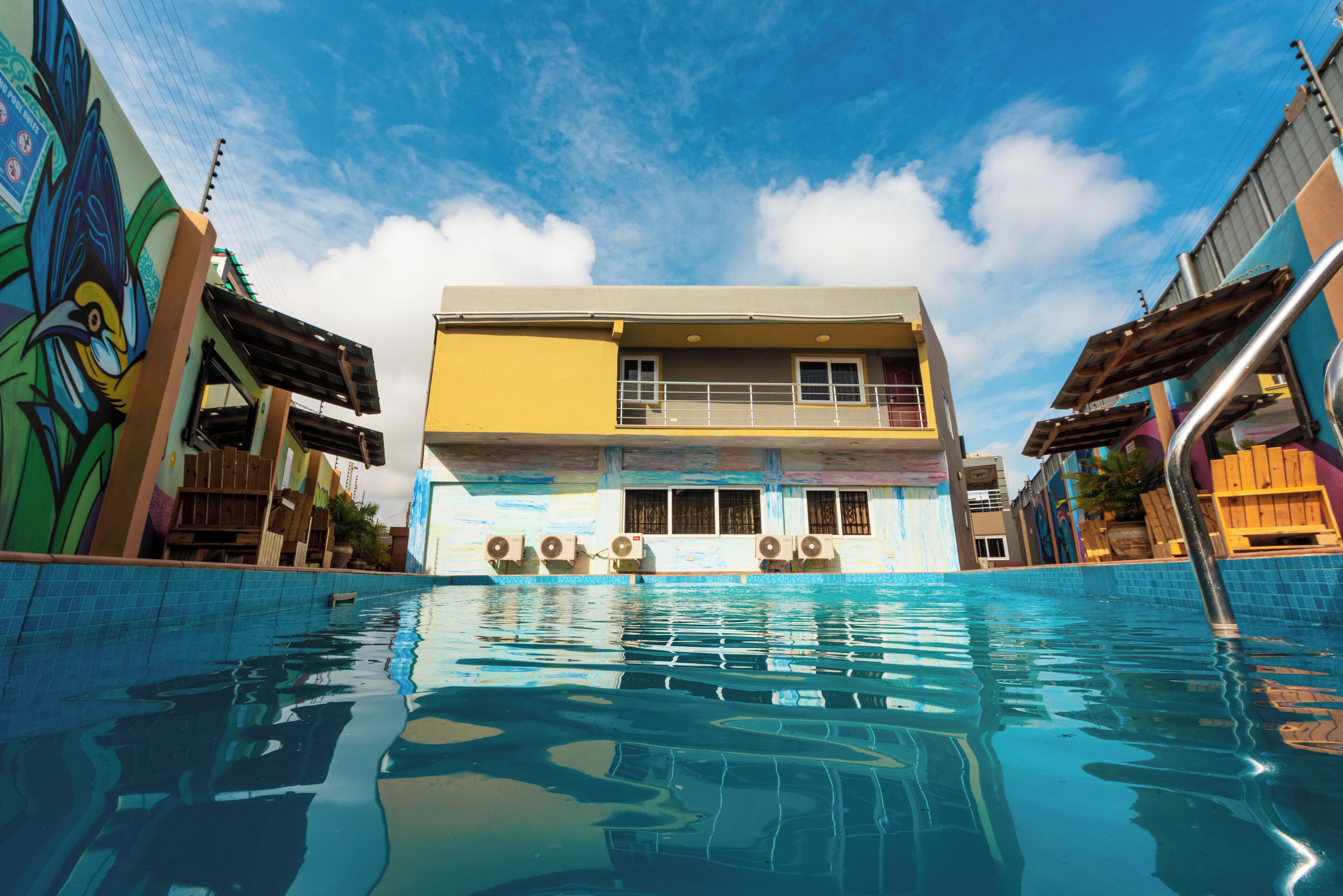 A hotel with a swimming pool, a two-story structure, and colorful murals on the exterior walls.