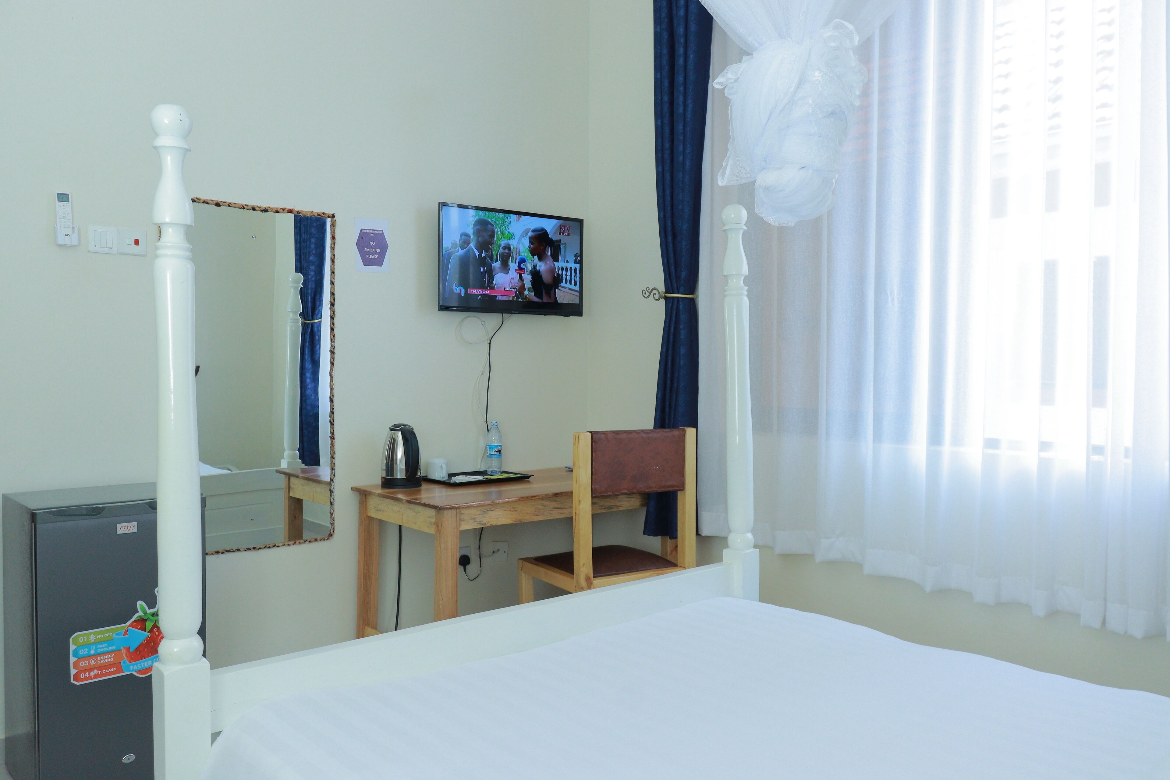 A hotel room with a bed, a desk with a chair, a television, and a wardrobe.