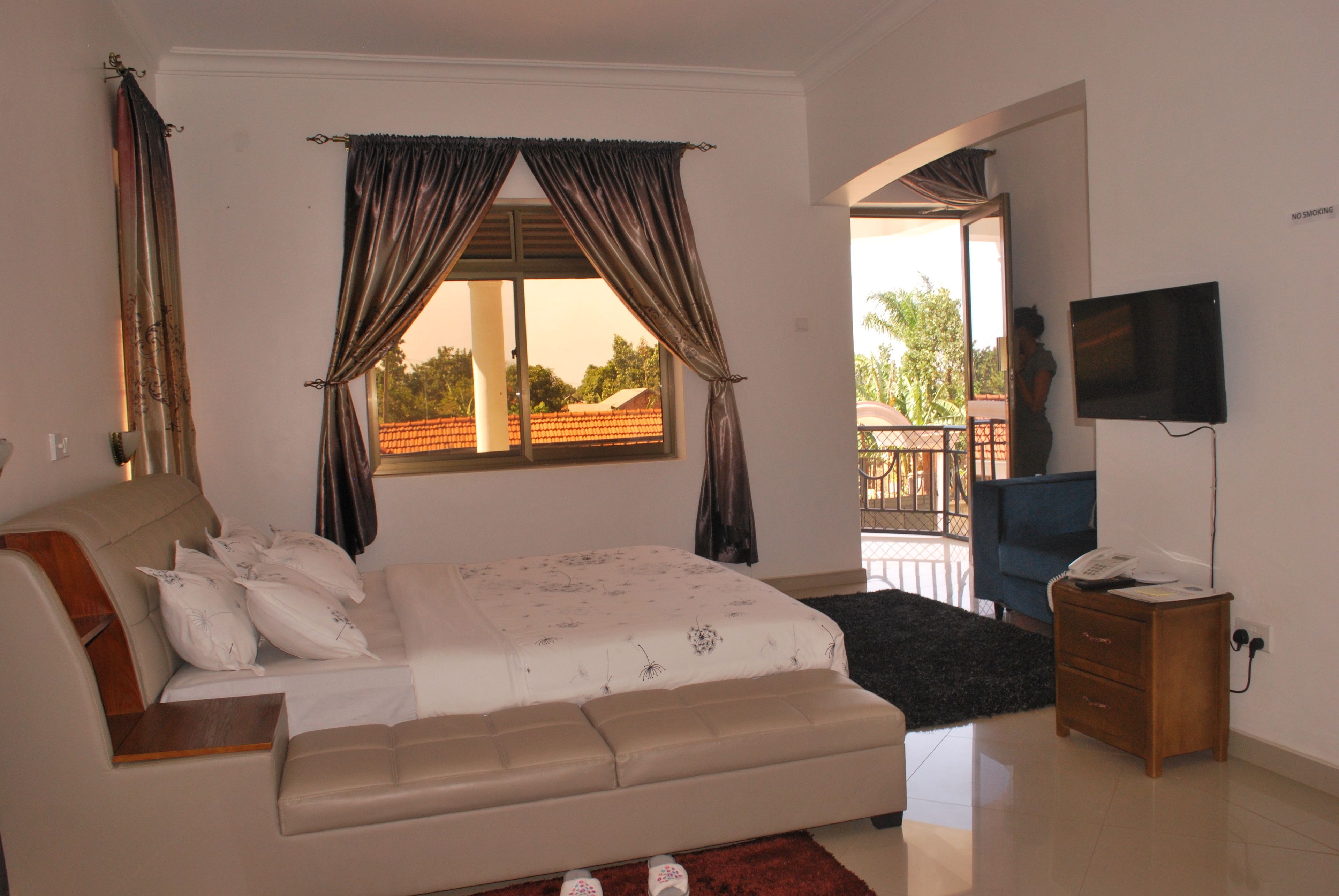 A bedroom with a bed, a TV, a desk, and a balcony.