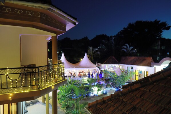 A terrace with a railing, a covered seating area, and a pool with lights. - Mowicribs Hotel & Spa (Entebbe)