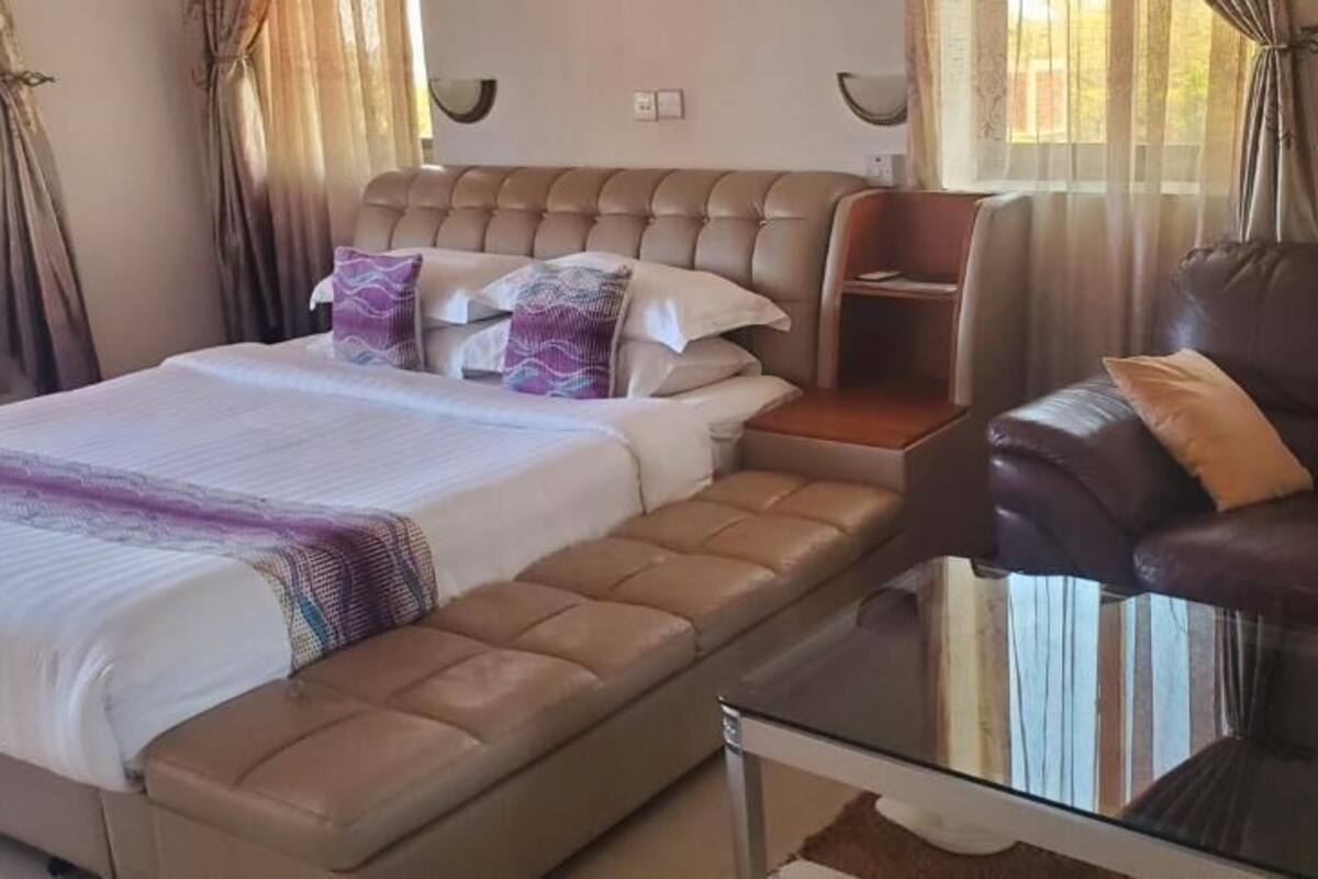 A bedroom with a bed, a sofa, and a glass table.