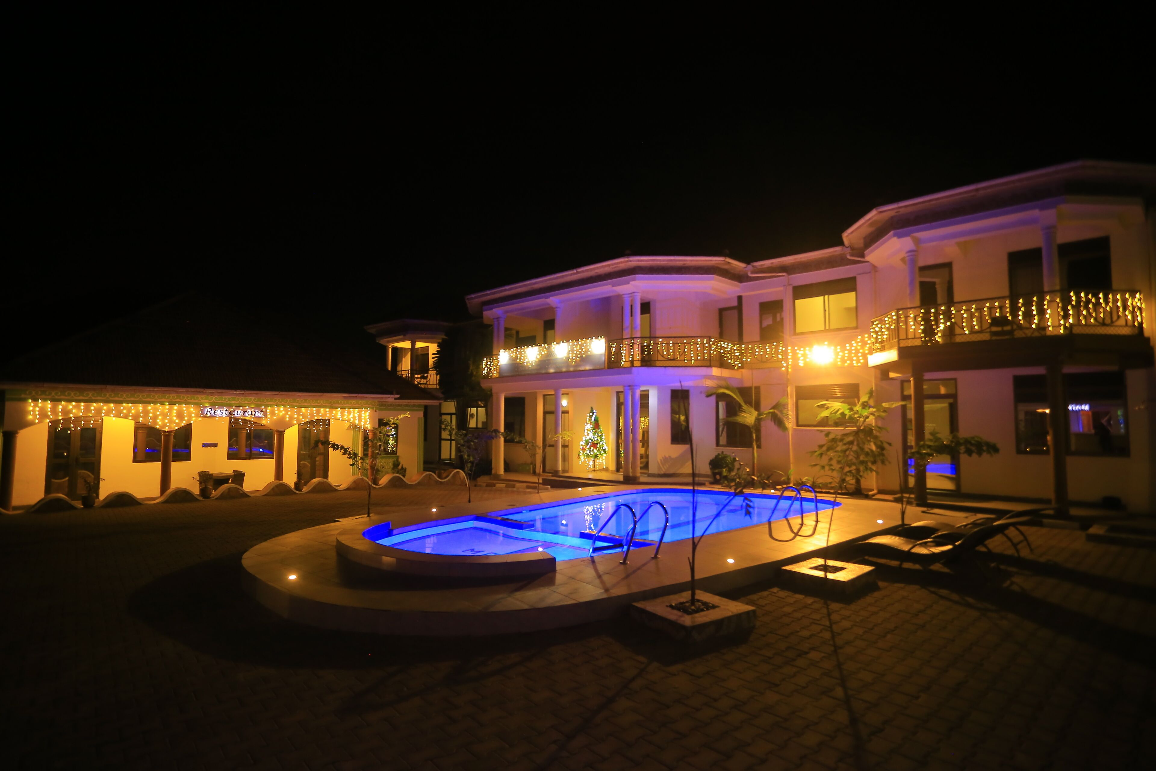 A large house with a swimming pool, a Christmas tree, and lights.