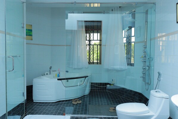 A bathroom with a glass-enclosed shower, a bathtub, and a toilet. - Mowicribs Hotel & Spa (Entebbe)