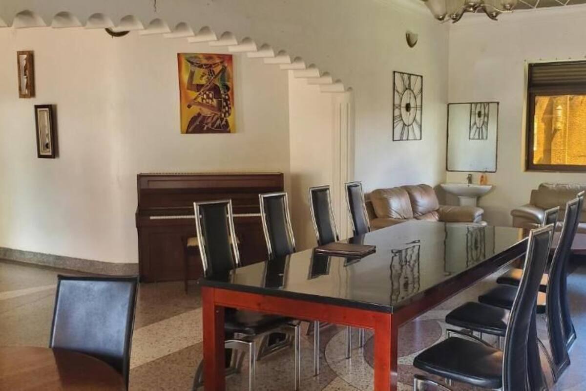 A spacious living room with a dining area, leather sofas, a fireplace, and a television.