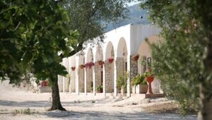 A building with a row of arches and potted plants. - Villaggio Riccio (Mattinata)