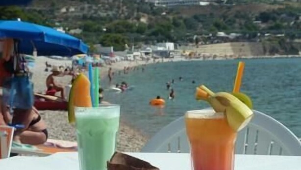 A beachside table with two drinks and a coconut shell. - Villaggio Riccio (Mattinata)
