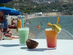 A beachside table with two drinks and a coconut shell. - Villaggio Riccio (Mattinata)