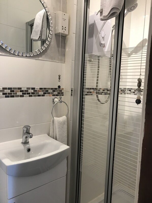 Un baño con ducha de vidrio, un lavabo blanco y un salpicadero de azulejos.