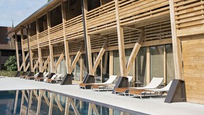 A modern building with a pool and lounge chairs.