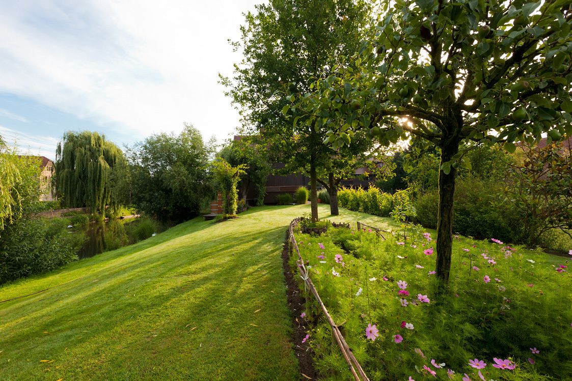 A well-maintained garden with a variety of plants and flowers, a neatly trimmed lawn, and a wooden fence.