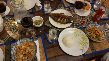 Una mesa de comedor con diversos platos, como arroz, pescado y una ensalada con anacardos.