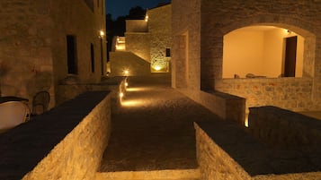 A narrow stone pathway leading to a building with a warm interior light.