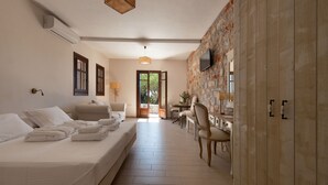 Una camera d'albergo con un letto, una scrivania, una sedia, una televisione e un muro in pietra.
