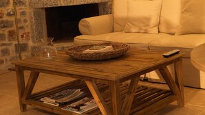 Un accogliente soggiorno con camino in pietra, un divano bianco e un tavolino in legno con riviste.