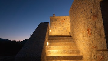 Una escalera de piedra que sube hacia un edificio con un muro de piedra a un lado.