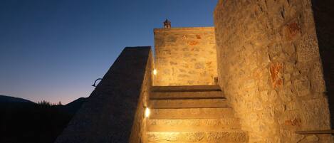 A stone staircase leading up to a building with a stone wall on one side.